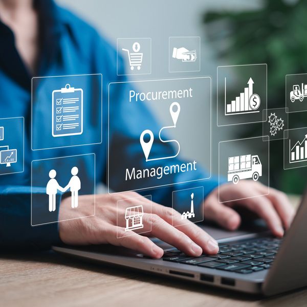 A person in a blue shirt works on a laptop with a white graphic overlay.