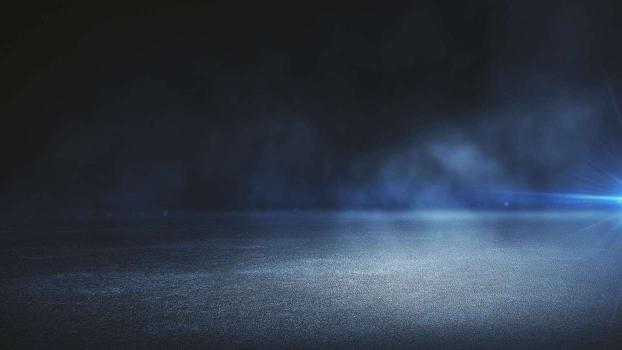 A rainy road with headlights in the distance.