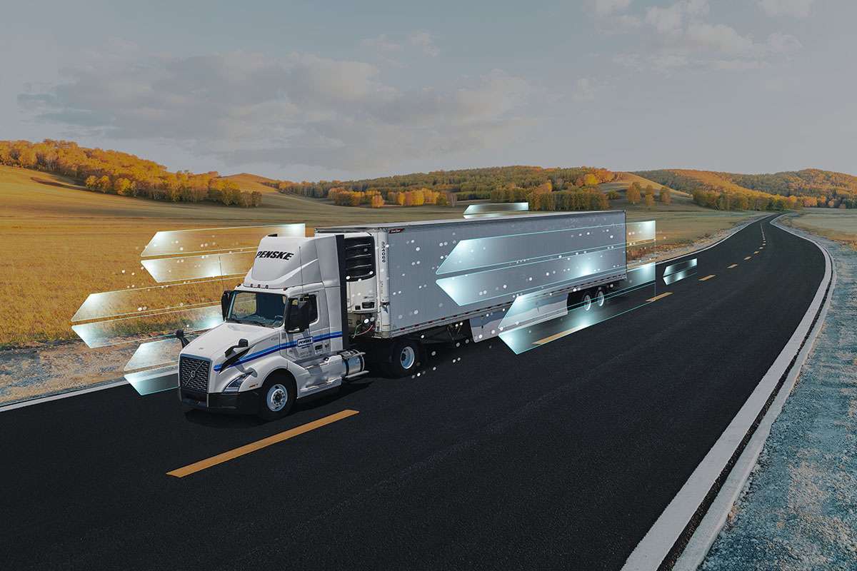 A white Penske semi-truck drives on the highway through the hills with a white digital overlay.