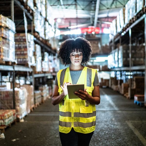 A women looks at an iPad while standing in a warehouse. 