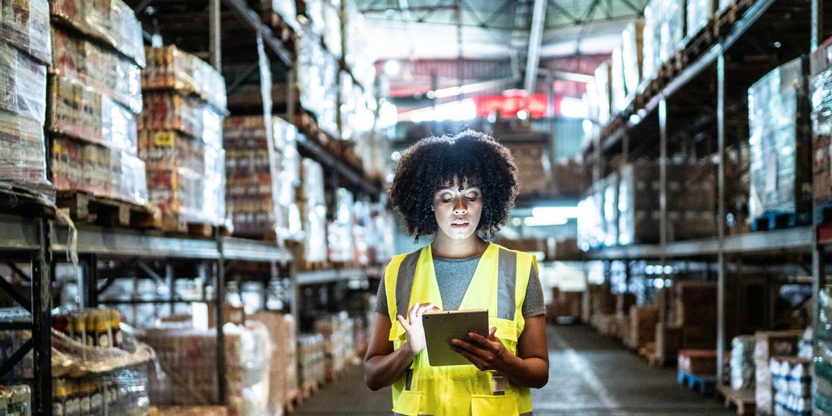 A women looks at an iPad while standing in a warehouse.