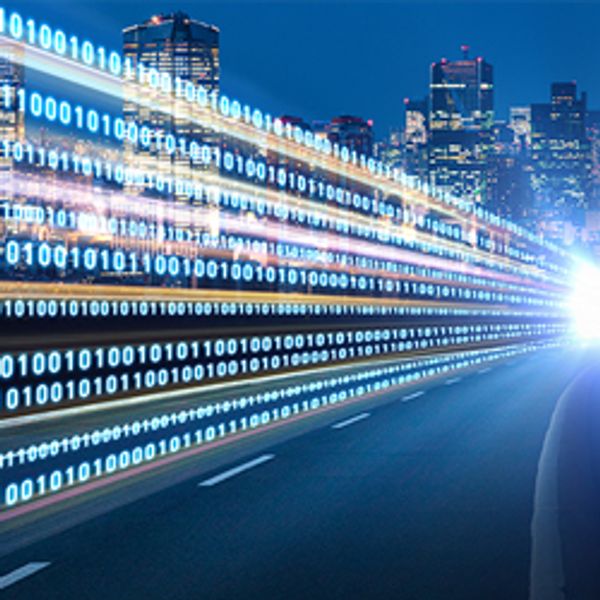 Digital zeros and ones fly over a road into a city.