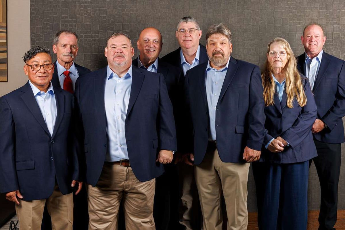 Eight drivers in business casual attire posing for a group photo.