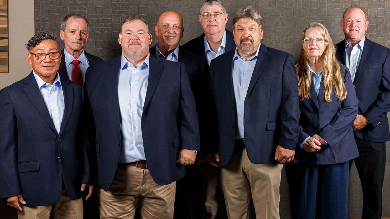 Eight drivers in business casual attire posing for a group photo.