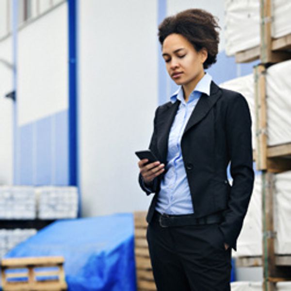 Woman looking at her phone in a warehouse environment