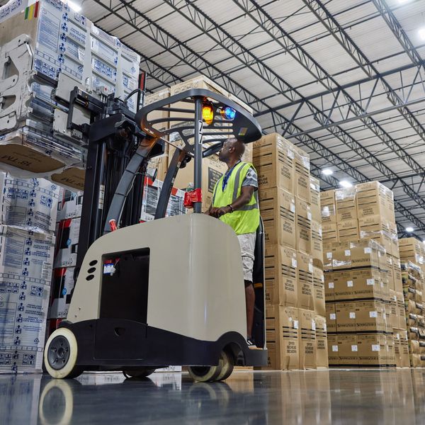 Warehouse workers manage boxes on a forklift.