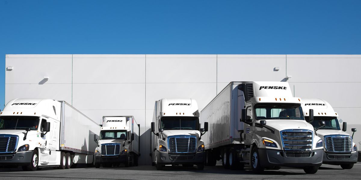 Penske trucks lined up at a warehouse.