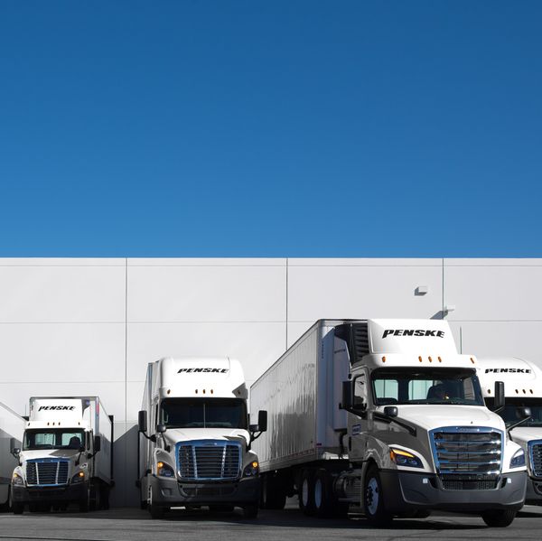 Penske trucks lined up at a warehouse.