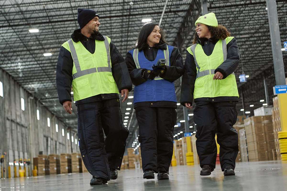 Three warehouse associates walking in a warehouse and talking