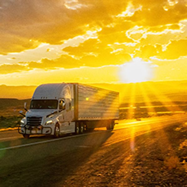 Tractor trailer traveling down a highway at sunrise