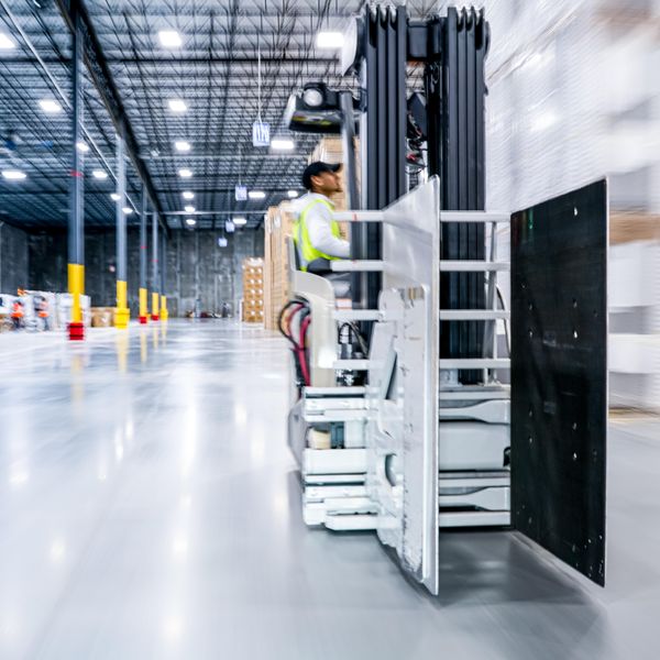 Warehouse employee stands on a piece of equipment.