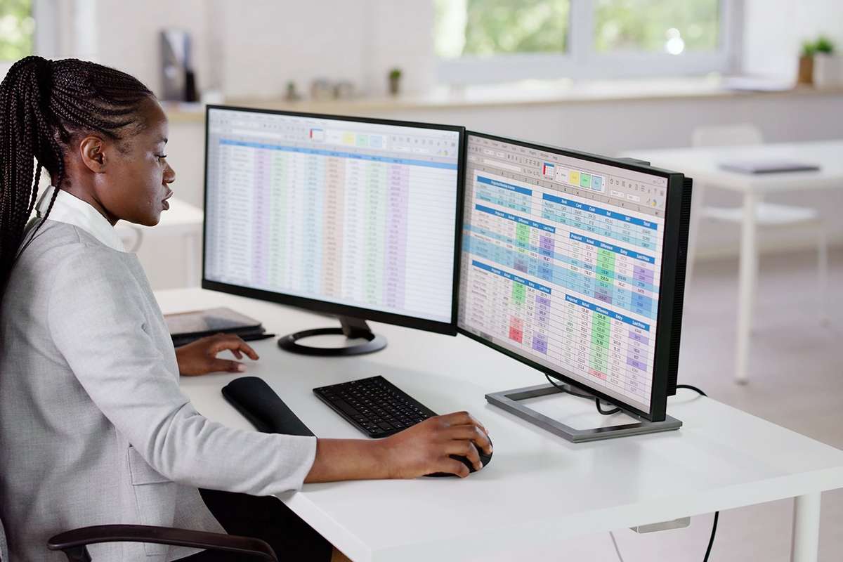 Woman sitting at a desk looking at two computer displays